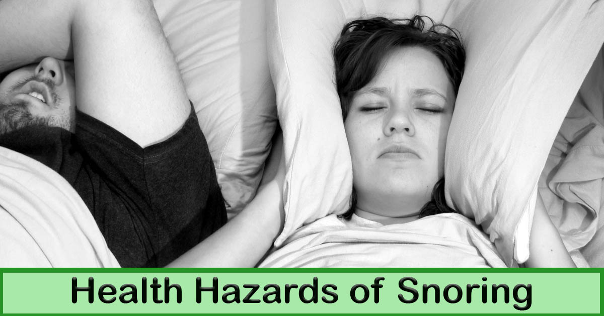 Health Hazards of Snoring. Picture of a caucasian male and female laying in bed sleeping. The female has her pillow pulled up over her ears.